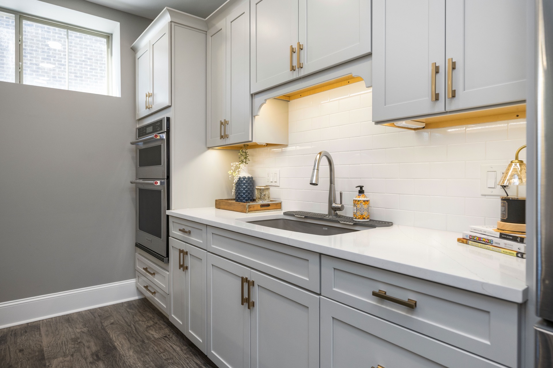 Basement kitchenette with gray cabinetry and under-cabinet light