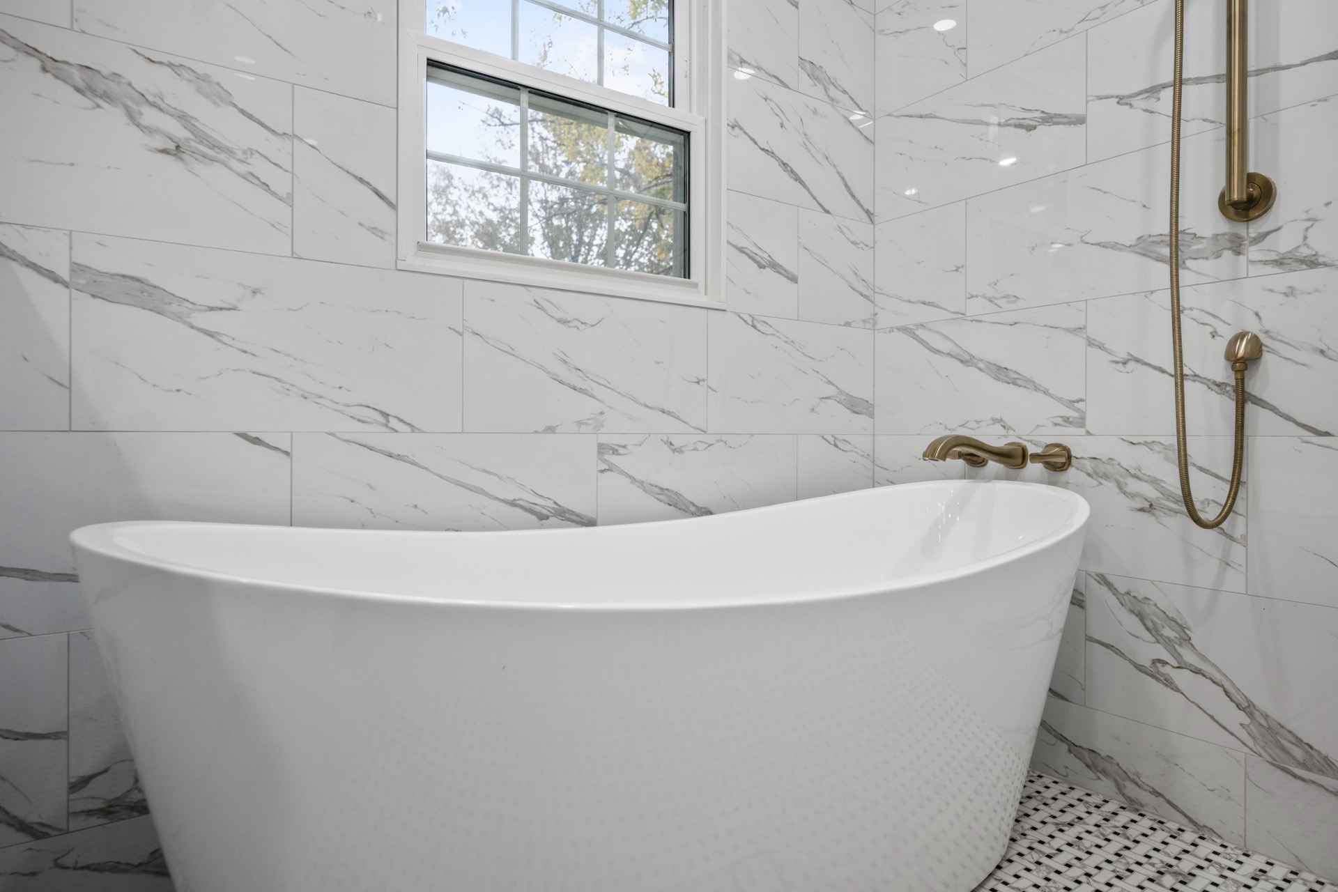 Freestanding tub with marble tile and brass fixtures