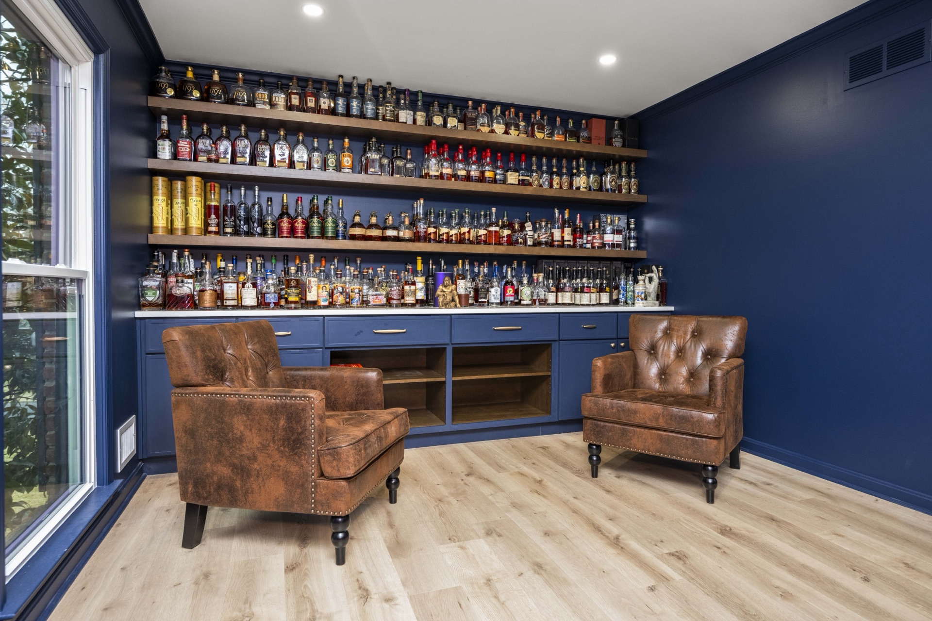 Floor-to-ceiling bourbon lounge with bottle library and leather club chairs at Lost Trail