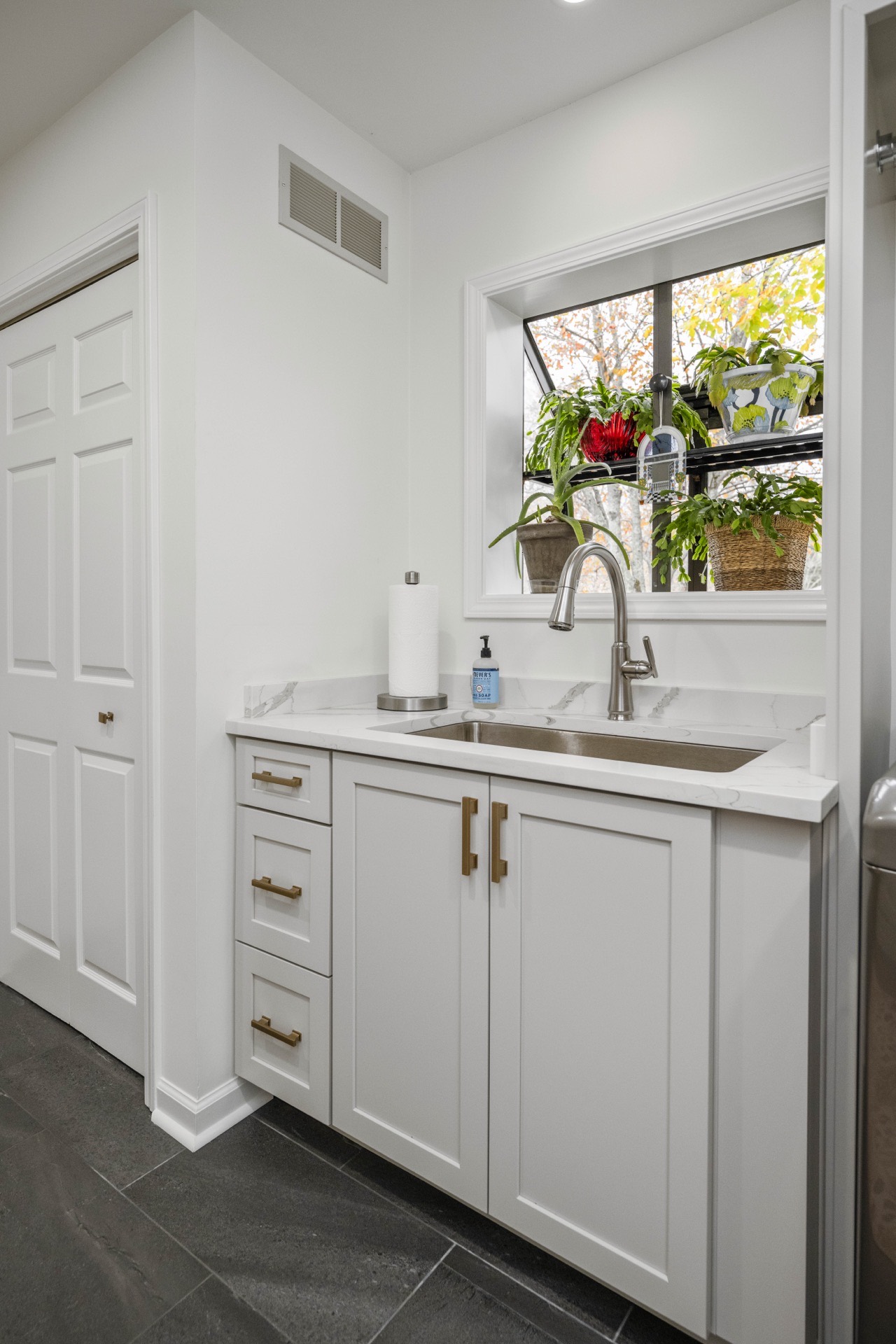 Detail of a marble kitchen island and brass faucet by Estate Renovations